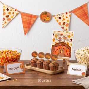 nurtuz home 3 Thanksgiving Little Turkey printable party set mockup featuring a banner, pumpkin cupcake toppers, food tents, and a party sign on a wooden table.